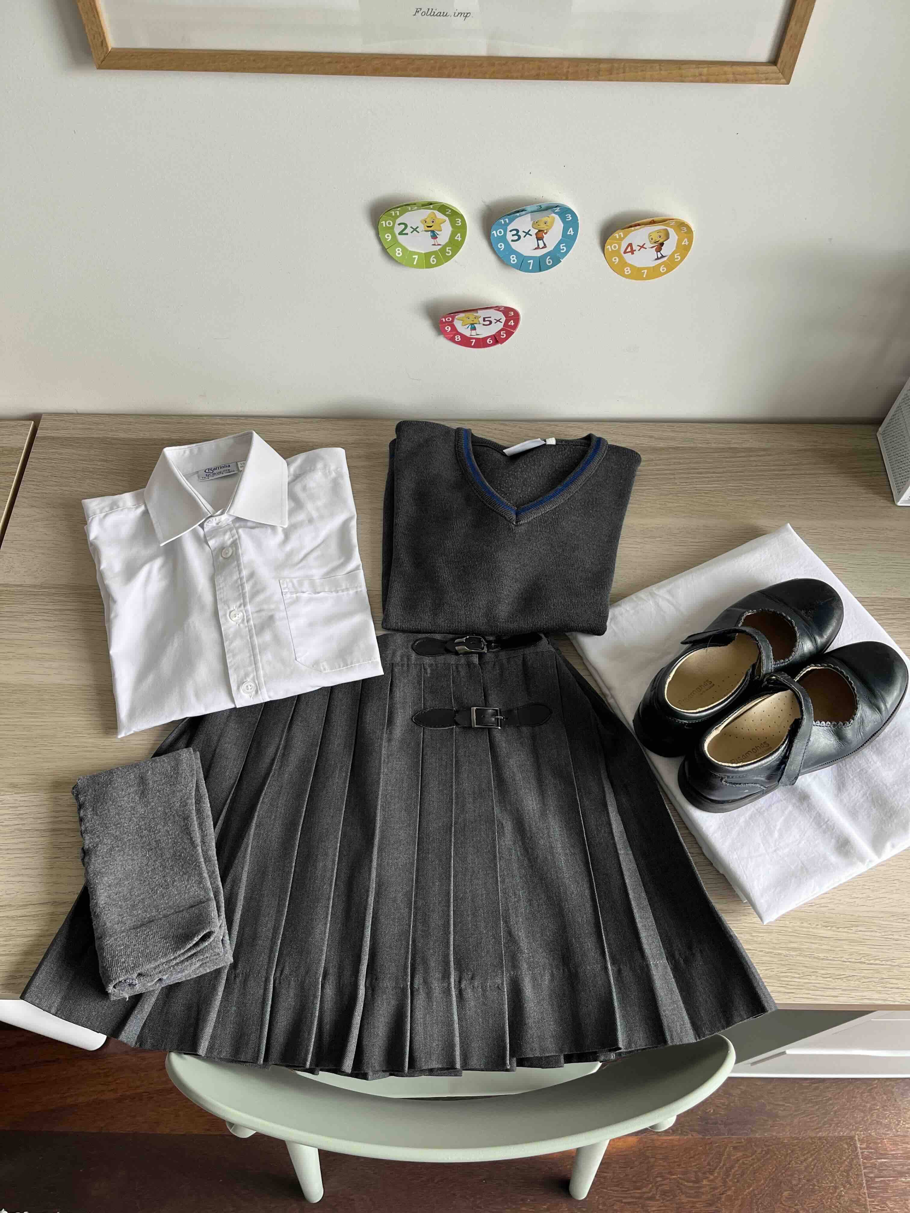 Base da farda da Hermione, só com o que seria usado por uma estudante não mágica com camisa, camisola, saia plissada, sapatos colegiais e collants cinzentos.